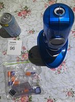 Top view showing the blue digital microscope and small accessories in a plastic bag with a soda can for size reference.