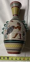 Full front view of the vase showing painted Egyptian figure and hieroglyphic motif, measuring tape at base showing about 16 inches high.