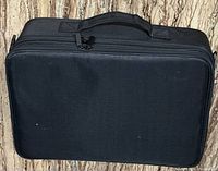 Front view of black zippered tool bag closed, showing rectangular shape and fabric texture.