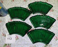 Top view showing all 5 green glass fan-shaped dishes arranged on a floral tablecloth.