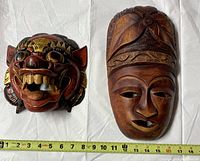Both wood masks side by side with measuring tape showing lengths about 12 inches each