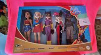 Photo of unopened boxed set of five DC hero dolls including Wonder Woman, Supergirl, Batgirl, Harley Quinn, and Catwoman.