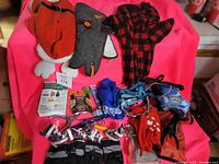 Overview of dog clothing including three jackets/coats, multiple dog socks and boots, various harnesses, and a nail clipper.