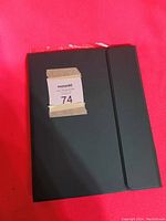 Closed black iPad case with magnetic flap closure on red background.