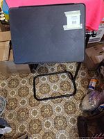 Black adjustable laptop/tablet table with rectangular top and metal frame shown from the top angle.