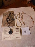 Photo of three necklaces on a table with Jade Maya packaging and information cards.