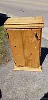 Closed pine cupboard showing wood grain and door with knob and lock.
