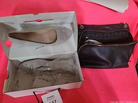 Photo showing pair of beige flat ballet shoes with bow in box alongside two black crossbody bags