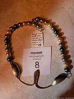 Full necklace including the two spoon handles, mother of pearl beads and the clasp.