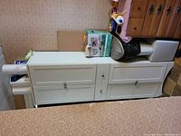 Front view of the white cupboard showing all four doors closed with a drawer in the middle.