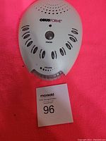 Front view of ObusForme white noise machine on a pink background with lot number 96 in front.