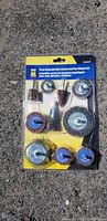 Full set of 10 assorted wire brushes and flap wheels in original packaging on concrete surface.