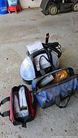 Two car emergency kits in soft bags containing tools and accessories such as flashlight, booster cables, rope