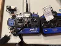 Eflite Blade SR HP6DSM 6-channel transmitter with visible control sticks, switches, and LCD screen, along with charger and cables on table