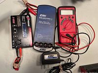 Full view of the three main electronic items: Extreme X-605 charger, Eflite Celectra charger, Amprobe multimeter with red and black leads coiled