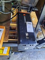 Top view of the TorqMaster garage door opener showing the main black casing with orange end caps and visible wear.