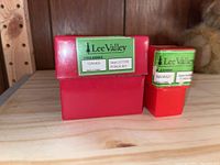 Two red plastic cases with green and white Lee Valley labels showing stock numbers and punch set type: one labeled 5mm Letter Punch Set #92W6826, the other 5mm Number Punch Set #92W6827.
