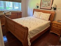 Full room view of pine sleigh bed assembled with coverlet and shams