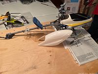 Side view of the Align Trex 450SE V2 helicopter showing full frame with canopy, rotor blades, tail boom, and landing gear on a wooden table.