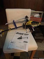 Yellow E-flite Blade 400 3D RC helicopter resting on a white chair with the user manual visible beneath it.