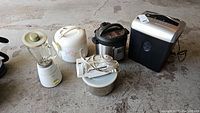 Photo showing five small appliances including blender, rice cooker, Instant Pot, iron, and shredder on concrete floor