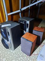 Photo showing four Sony speakers, two large with black and silver casing and two smaller wood-finish speakers