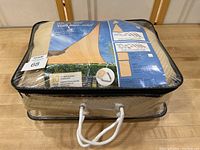 Packaged backyard patio shade sail in a clear zippered plastic bag with handle, displaying product and brand details.