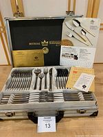 Full set of Bestecke Solingen cutlery with 24 Carat gold detailing inside original metal case, includes brochures and certificate, case interior shows wear.