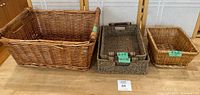 Four different wicker baskets arranged on a wooden surface showing their size difference and weave styles.
