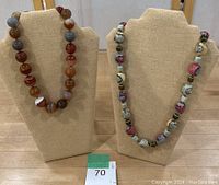 Photo of two statement necklaces on display stands showing the overall appearance of the necklaces.