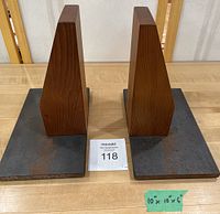 Pair of modern bookends with wooden arms and heavy metal bases shown from top down on table with measurement note.