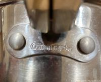 Close-up photo showing Cuisinart brand marking on stainless steel handle fixture of pot or pan.