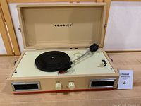 Front angled view of the Crosley record player's open lid, tone arm, platter, and control knobs.