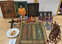 Full display showing various multi-faith religious items laid out on a table, including plaques, framed photographs, bead malas, and small icons.