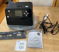 Black combo album scanner with screen, buttons, slider switch and cables on a wooden surface.