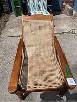 Front view showing curved cane seat and backrest within teak frame