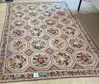 Full view of rug laid on floor showing overall pattern of octagonal floral panels and rose border