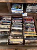View of multiple DVD cases arranged in several compartments with titles ranging from documentaries, historical movies, Lord of the Rings, Bible related videos, and some apocalyptic films.