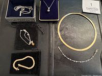 Six gold necklaces and bracelets displayed on velvet and leather pads