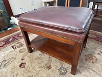 Side view of the leather ottoman showing wooden frame and lower shelf