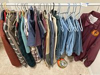 Hanging men's casual clothes including shirts, sweaters, jackets, and denim jeans in sizes L and XL.