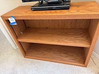 Front view of oak wood bookshelf showing two shelves and open space for the extra shelf.