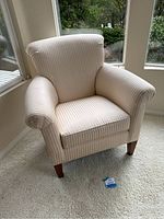 Front angle view of the white fabric side chair showing subtle vertical stripes and wooden legs.