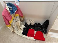 Vintage women’s colorblock one-piece snowsuit in pink, yellow and cream with blue lining displayed with boots and winter accessories.