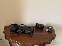 Wide shot showing all items in the lot on a wooden table including camera, case, manual, and flash unit.