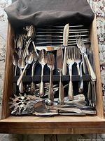 Drawer of assorted stainless steel cutlery including forks, knives, spoons, and serving utensils.