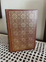 Front cover of the book showing brown leather cover with gold embossed floral designs