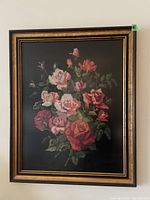 Frontal photo of framed floral artwork showing a bouquet of roses with green leaves on dark background.