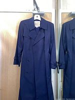 Full length photo of navy blue London Fog pea coat hanging on door, showing double-breasted style, buttons, collar, and sleeve details.