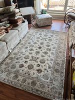 Full view of the rectangular oriental style area rug on hardwood floor in living room setting, showing detailed floral patterns and borders.